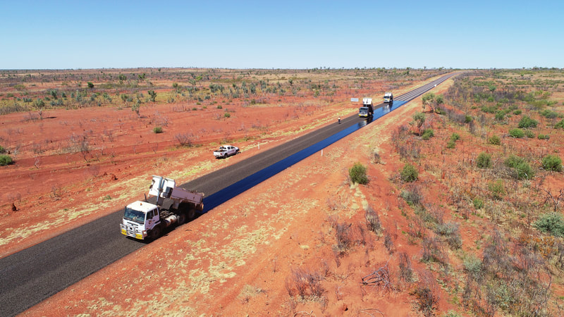A Tipper spreading aggregate over freshly sprayed bitumen near Alice Springs..